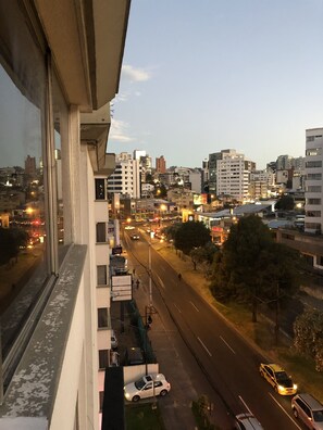 A cityscape viewed from a high vantage point, featuring a wide road with vehicles, buildings of various heights, and a clear sky. - Suite and Apartment Well Located In Quito (Quito)