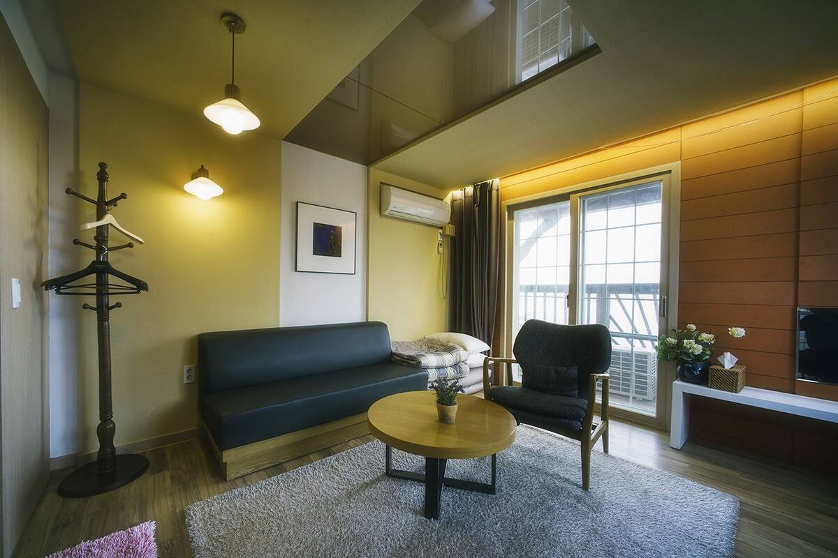 A modern living room with a sofa, armchair, coffee table, and a coat rack.