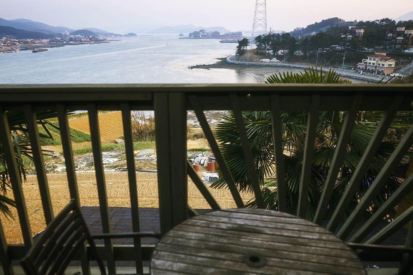 A balcony with a view of a river, a distant bridge, and a tower.