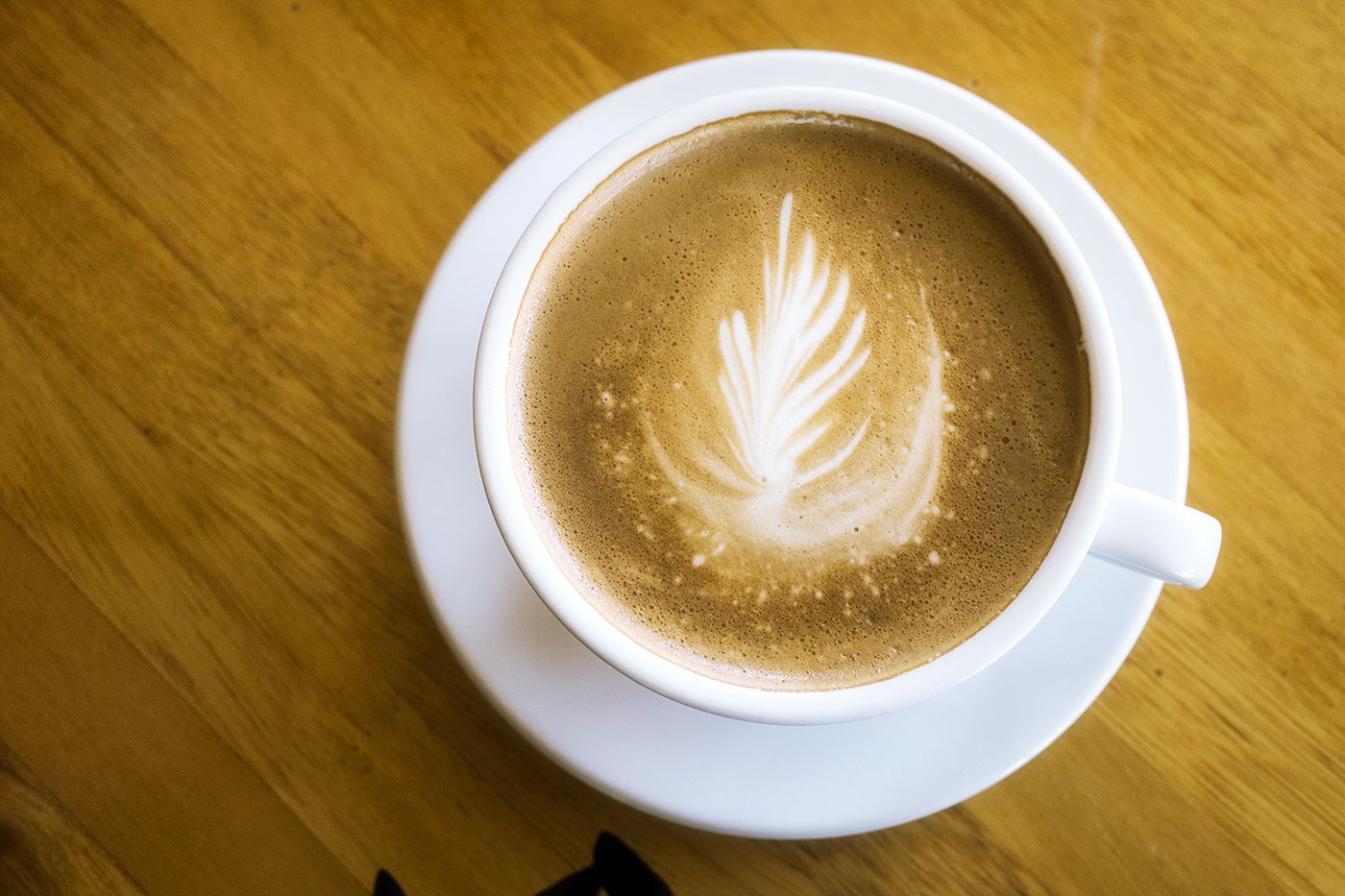 A cup of coffee with latte art on a wooden table.