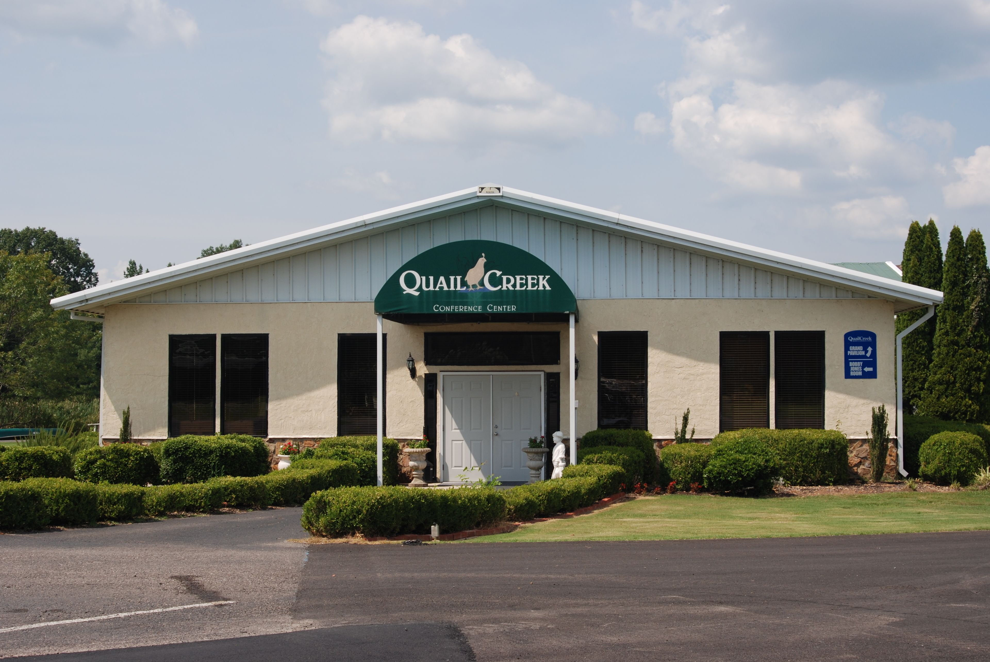A building with a sign reading "Quail Creek Conference Center" and a well-maintained lawn in front.