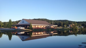 A building with a sign reading "The Inn" reflecting in a calm body of water. - The Golf Inn at QC Resort and RV (Hartselle)