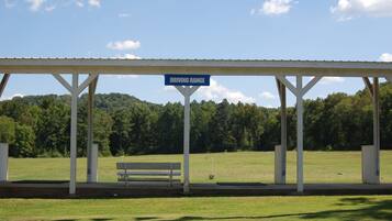 A covered area with a sign reading "DRIVING RANGE" and a bench.