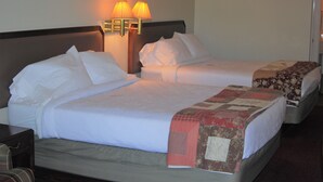 A hotel room with two beds, a nightstand, and two wall-mounted lamps. - The Golf Inn at QC Resort and RV (Hartselle)