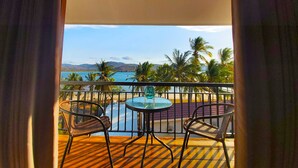 Un balcone con un tavolo rotondo e due sedie, con vista sulla spiaggia e sul mare.