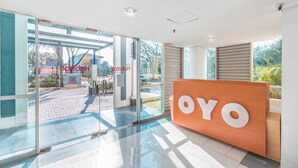 A hotel reception area with a glass door entrance, a reception desk with the logo "OYO", and a view of the outside. - OYO Flagship 1170 The Habitat Karawaci (Curug)