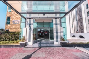A modern hotel entrance with a glass facade, a prominent 'OYO Flagship' sign, and a clear pathway leading to the entrance. - OYO Flagship 1170 The Habitat Karawaci (Curug)
