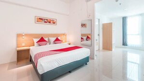 A modern hotel room with a large bed, bedside tables, a mirror, and a door leading to another room. - OYO Flagship 1170 The Habitat Karawaci (Curug)