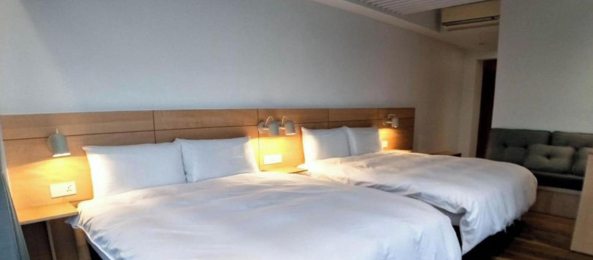 A double bed with a wooden headboard, two bedside lamps, and a neutral color scheme.