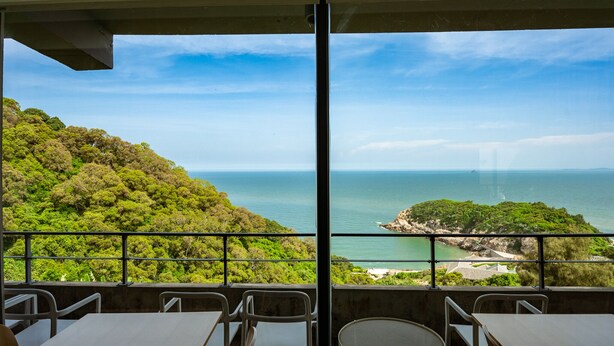 A terrace with a view of the sea and a green hillside. - Day Spring (Nangan)