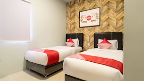 Habitación de hotel con dos camas, cada una con ropa de cama roja y blanca, un revestimiento de pared de madera con patrón de espiga y un cuadro con la palabra 'ovo' y un diseño floral.