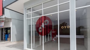 Fachada con grandes ventanales de vidrio y un llamativo logotipo circular rojo.