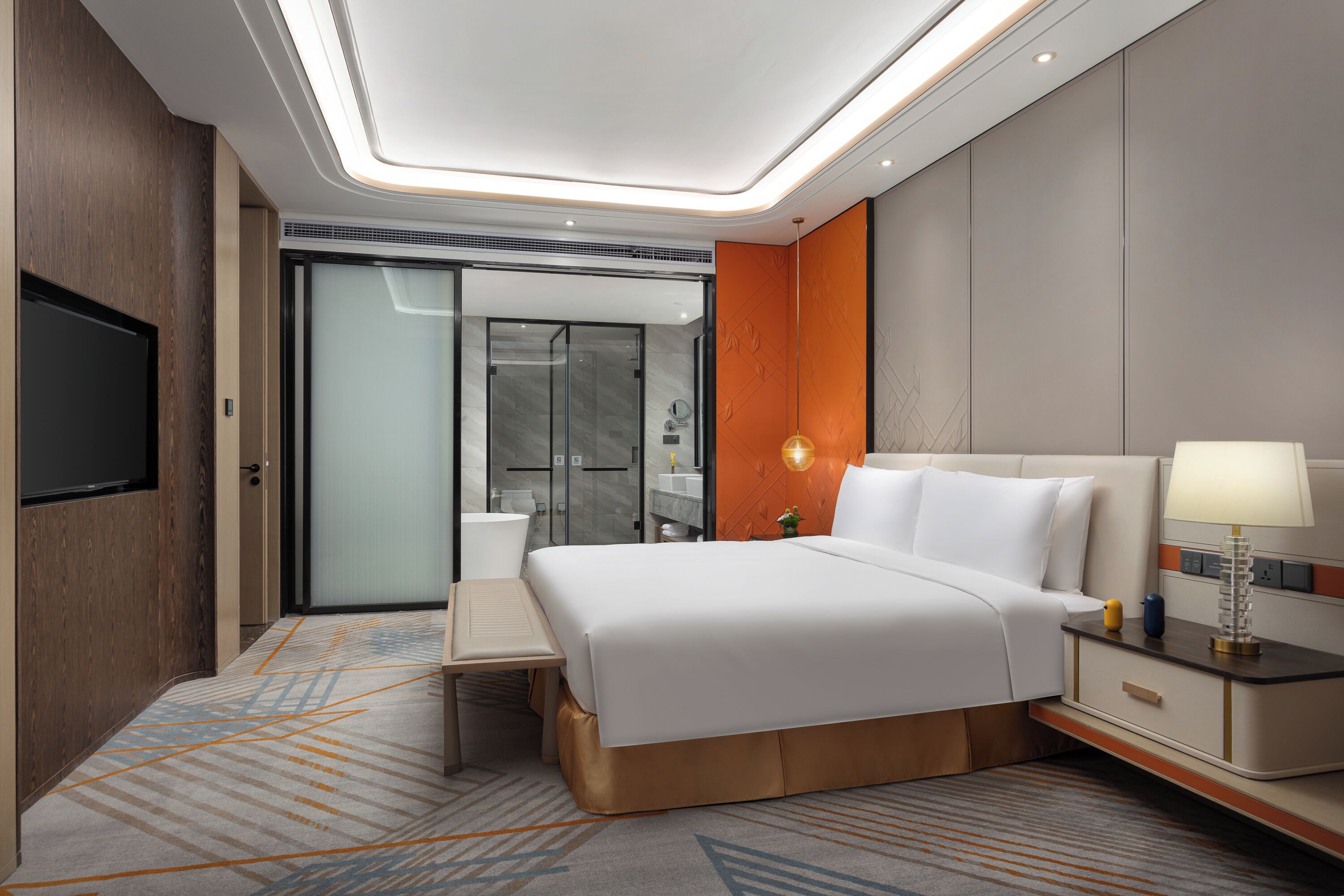 Een moderne hotelkamer met een groot bed, nachtkastje en een aan de muur bevestigde televisie.