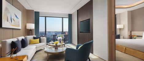 A modern hotel room with a sofa, armchair, coffee table, and a bed.