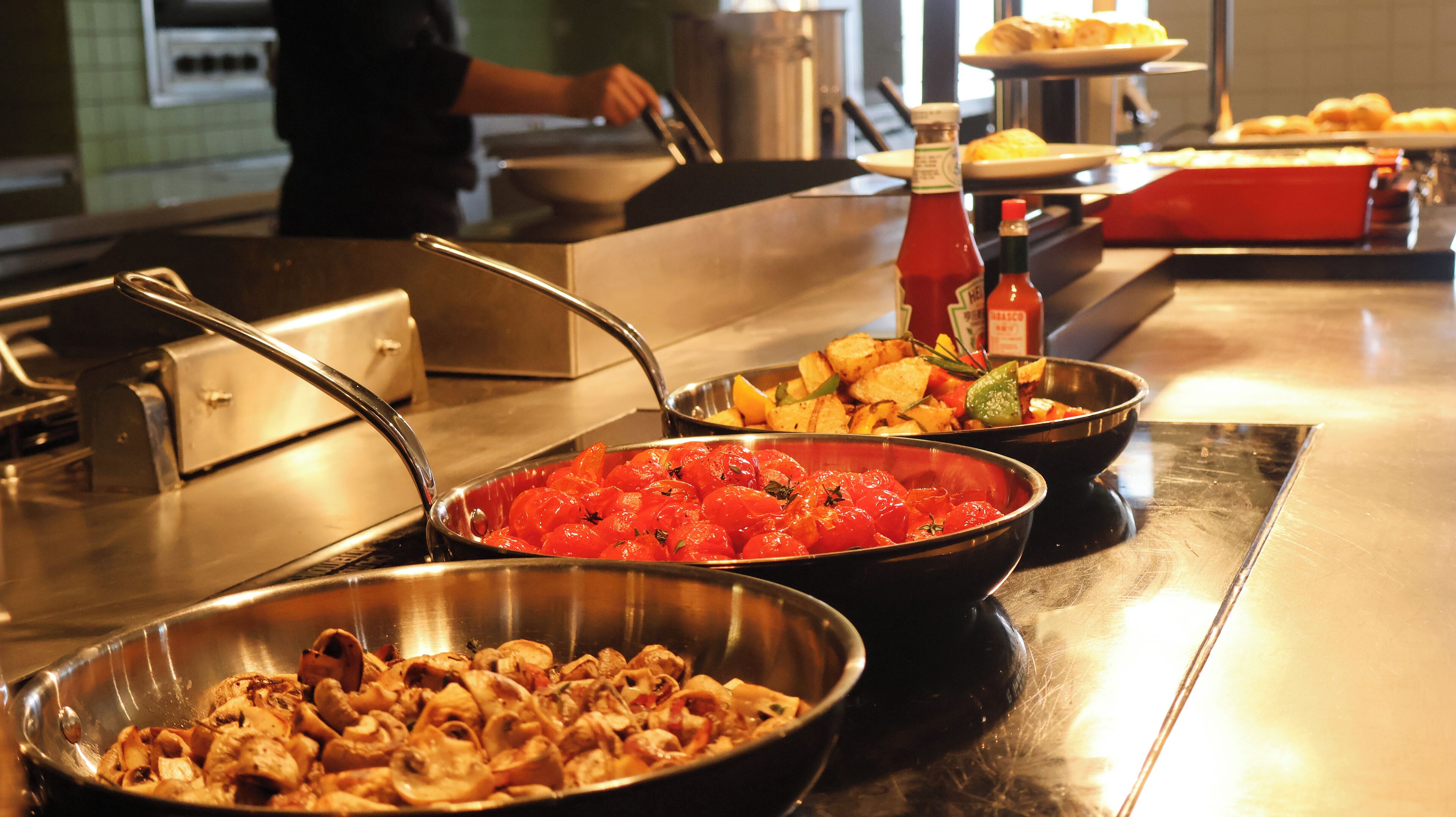 A buffet with various dishes including roasted vegetables, a red sauce, and a meat dish.