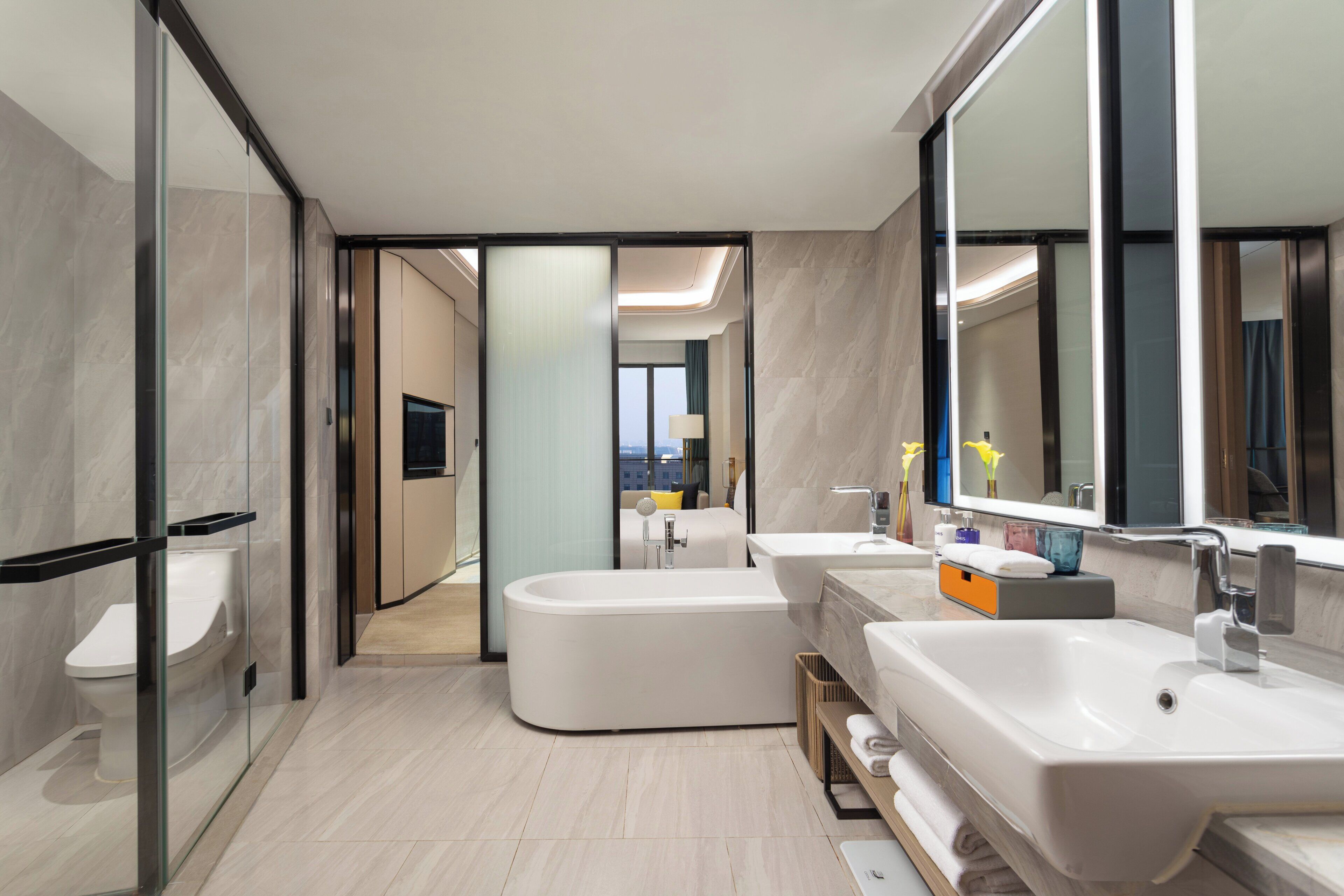 A modern bathroom with a freestanding bathtub, two sinks, and a large mirror.