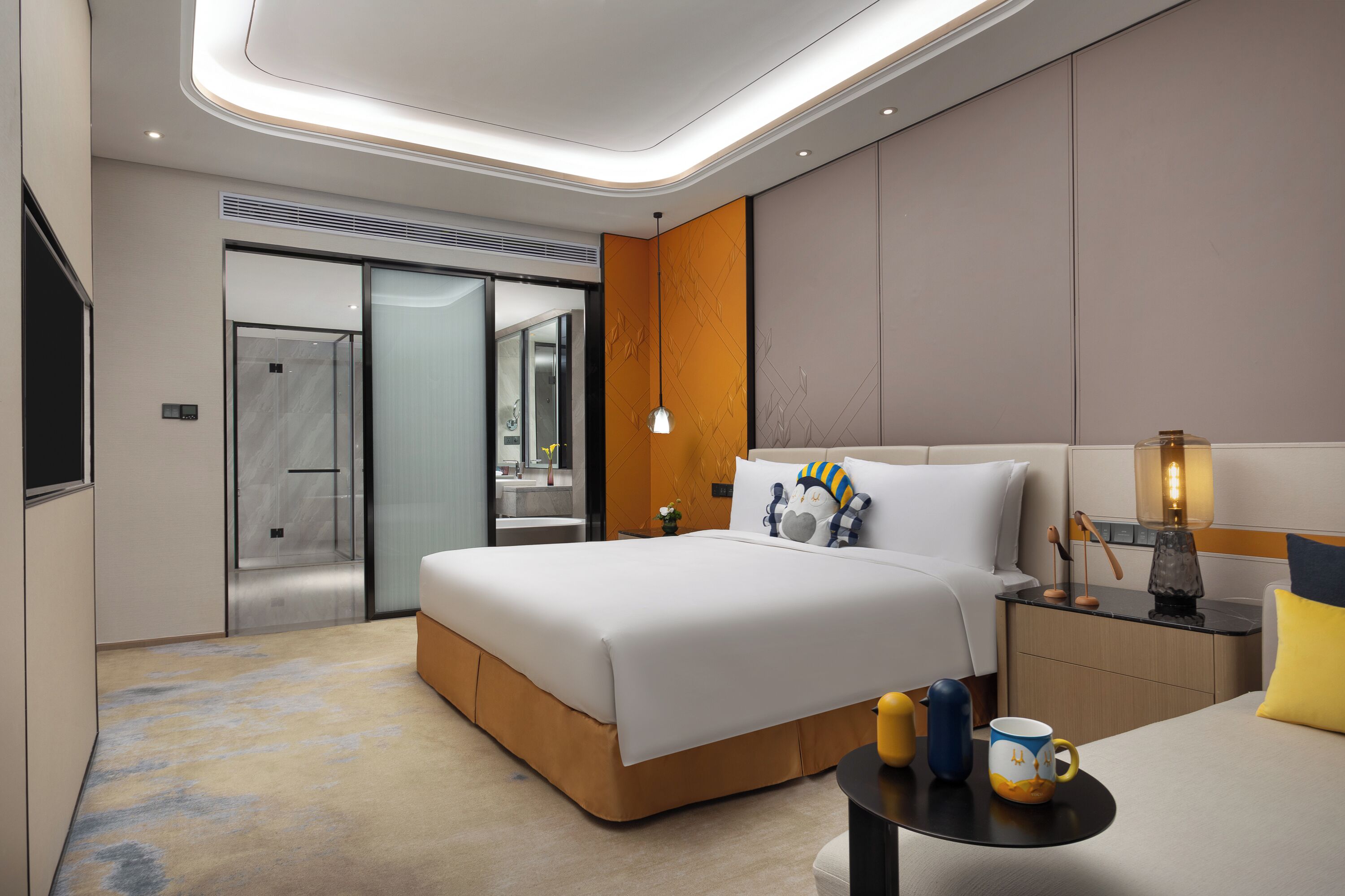 Ein modernes Hotelzimmer mit einem großen Bett, Nachttisch, Lampe und Blick auf die Stadt.