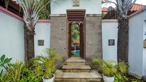 A set of stone steps leading to a doorway, flanked by potted plants and a small pool visible through the doorway. - The Georgina Estate (Nusa Dua)