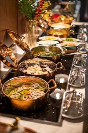 A buffet table with various dishes in metal serving dishes.
