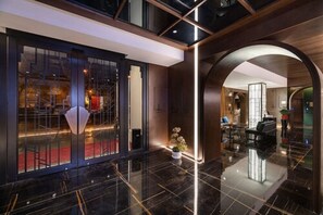 A modern hotel lobby with a glass entrance, a reception desk, and a seating area.