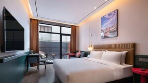 Una habitación de hotel moderna con una cama grande, un escritorio y una ventana con cortinas.