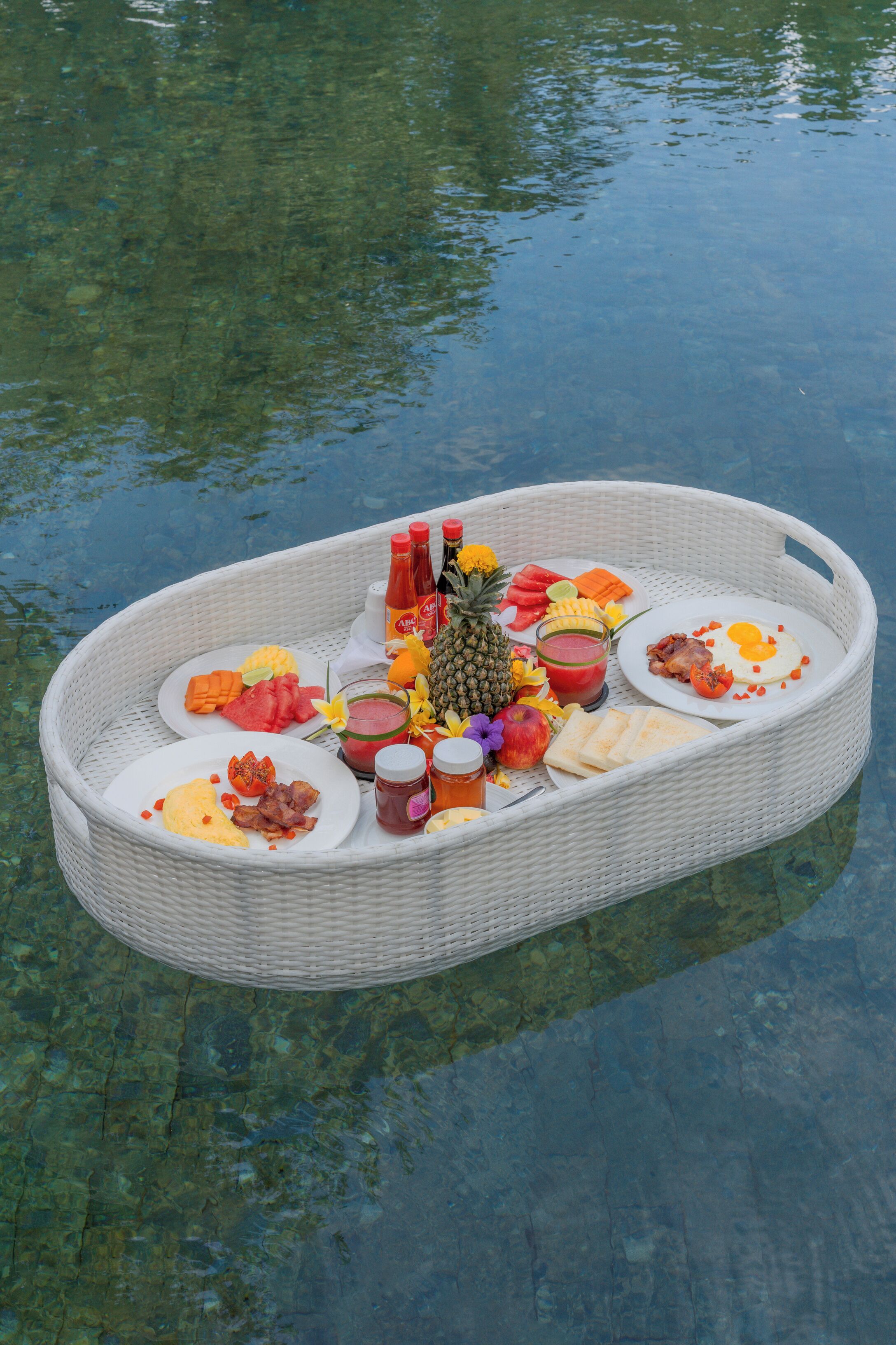 Un montaje flotante para comer, con diversos alimentos y bebidas sobre una superficie de agua transparente.