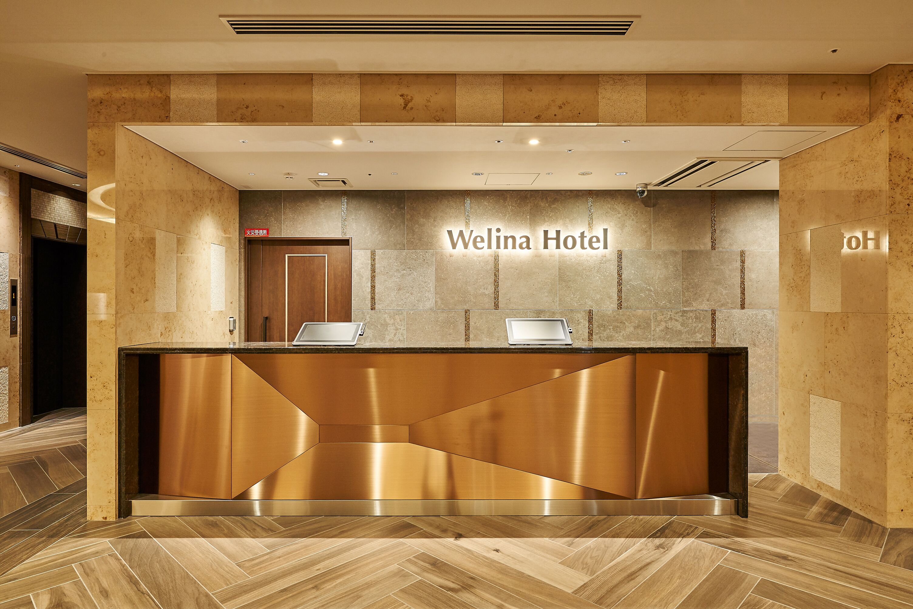 Uma receção com design moderno, um letreiro indicando "Welina Hotel" e um chão com padrão losango.