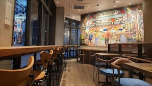 A restaurant interior with wooden tables and chairs, a mural on the wall, and a view of the street outside. - Welina Hotel Premier Nakanoshima EAST (Osaka)