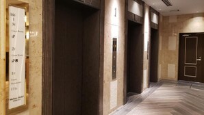 A hotel lobby with a herringbone-patterned floor, a reception desk, and three elevators. - Welina Hotel Premier Nakanoshima EAST (Osaka)