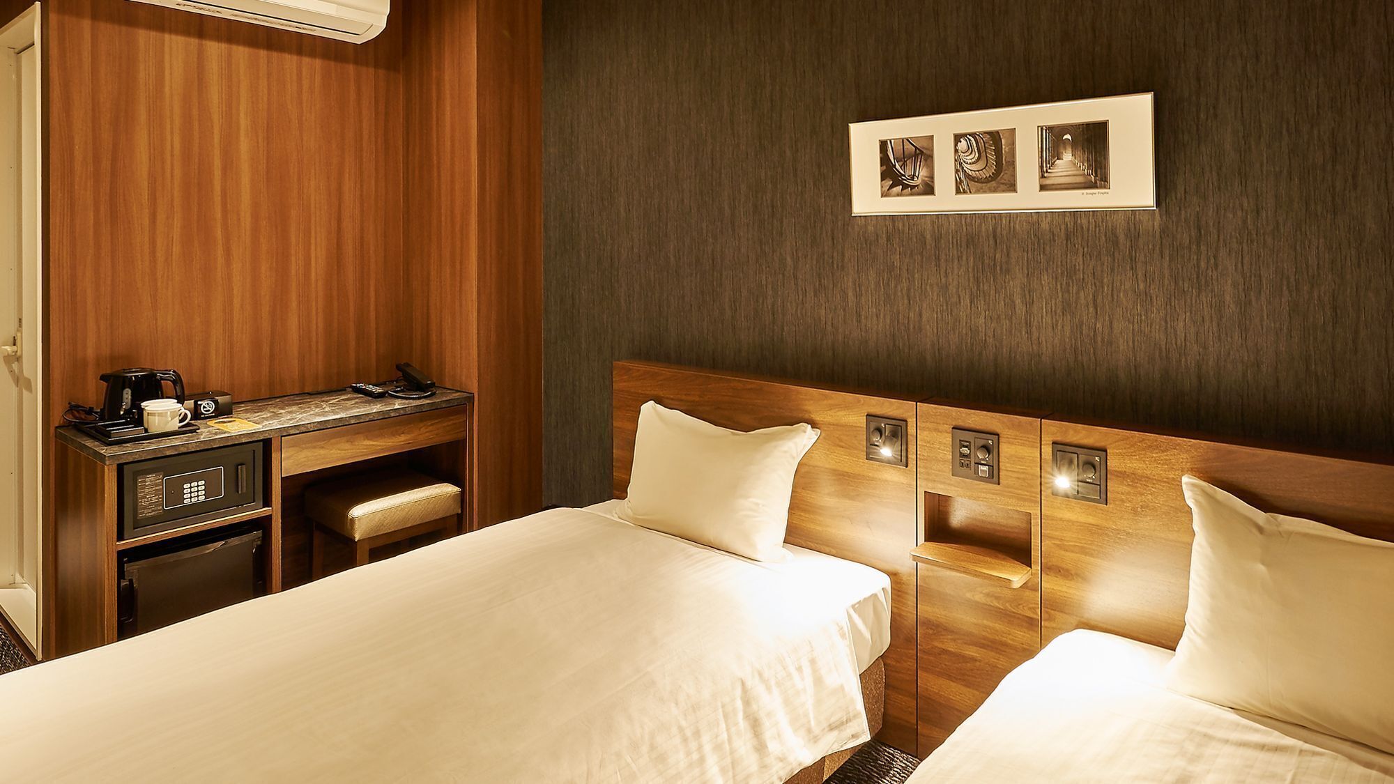 Ein Hotelzimmer mit zwei Betten, einem Schreibtisch mit Kaffeemaschine und einem an der Wand hängenden Bild.