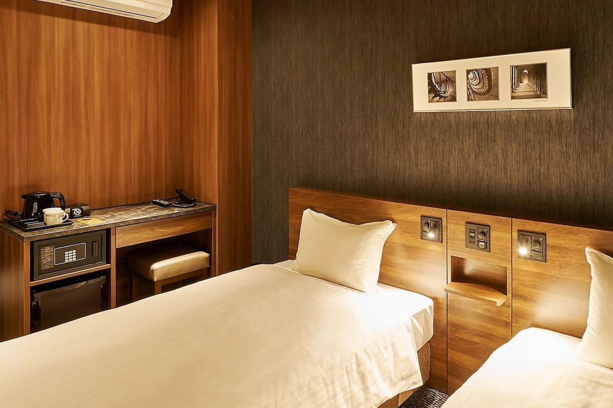 Une chambre d’hôtel avec deux lits, un bureau doté d’une machine à café et un tableau accroché au mur.