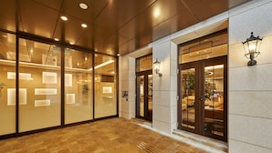A spacious lobby with a tiled floor, glass doors, and wall-mounted lighting fixtures. - Welina Hotel Premier Nakanoshima EAST (Osaka)