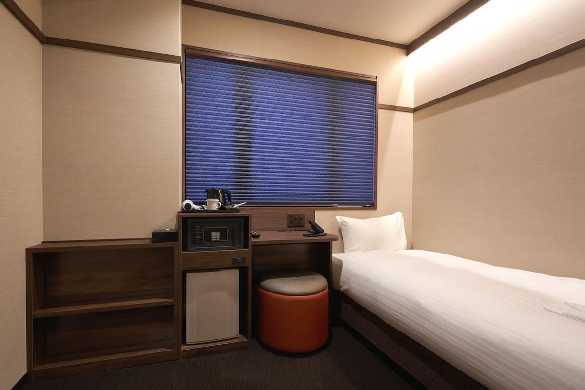 Ein Hotelzimmer mit einem Bett, einem kleinen Schreibtisch mit Mikrowelle, Telefon und Mülleimer.