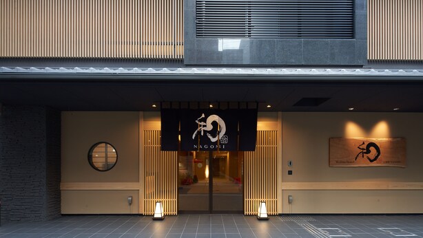 En modern hotellentréd med en svart skylt där det står ”Nagomi”.