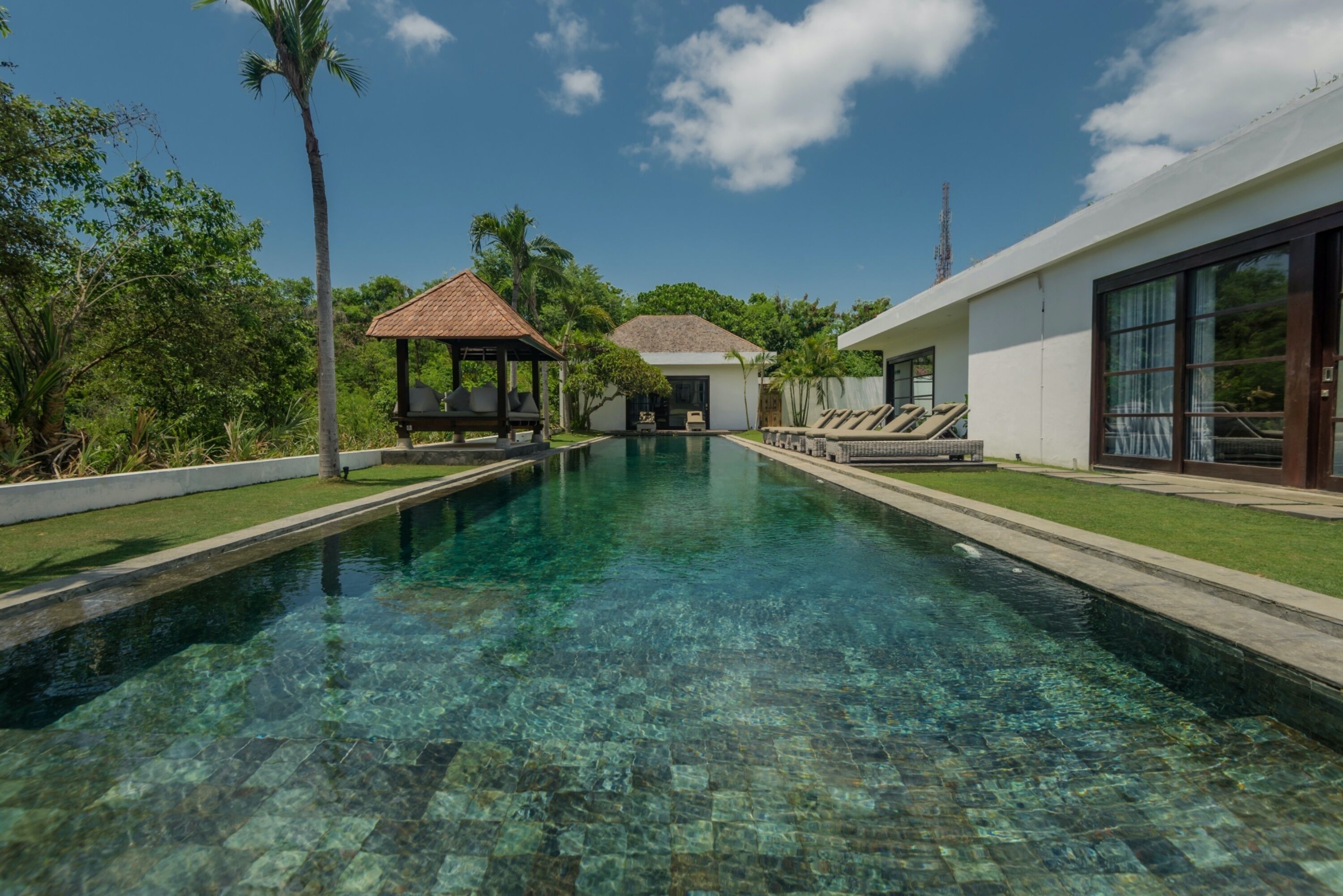 Ein klares Schwimmbecken mit einem Gazebo und einem Haus im Hintergrund.
