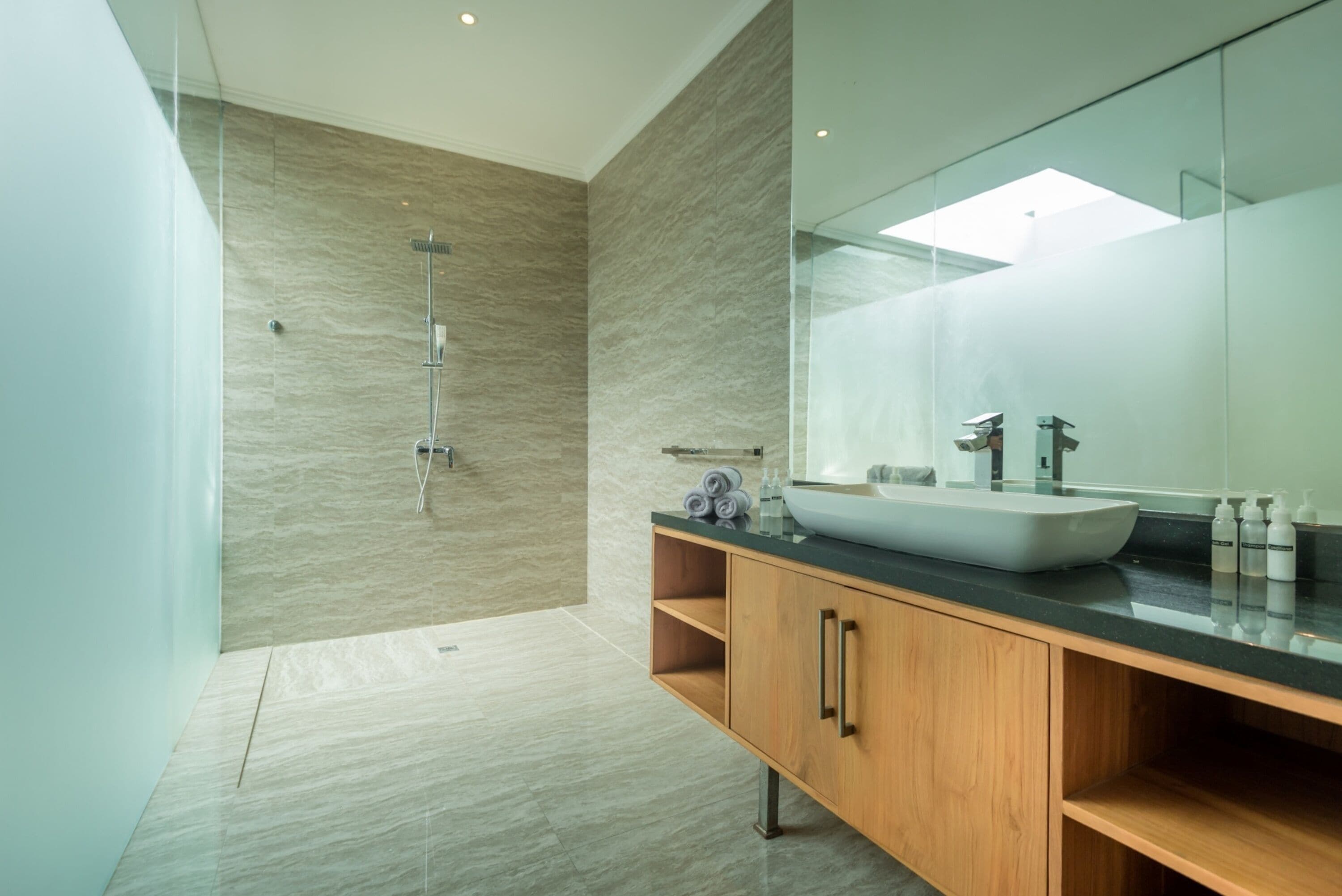 A modern bathroom with a large mirror, a vessel sink, and a shower.