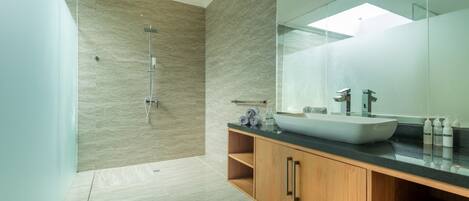 A modern bathroom with a large mirror, a vessel sink, and a shower.