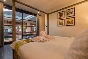 Habitación de hotel con una cama grande, un balcón con vistas y cuadros en la pared.