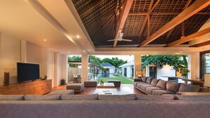 A spacious living room with a large sofa, a television, and a ceiling fan.