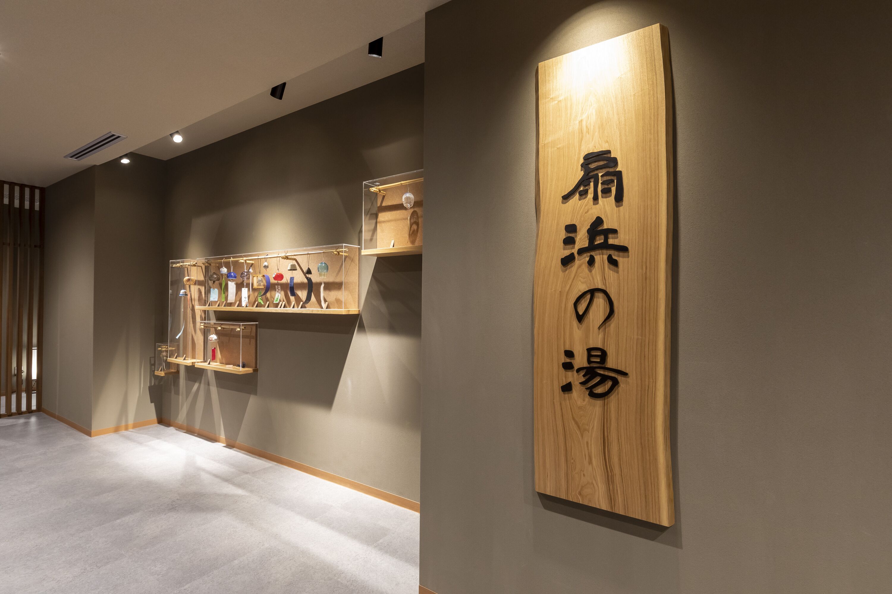 A wooden sign with Japanese characters, a display of handbags, and a modern interior design.