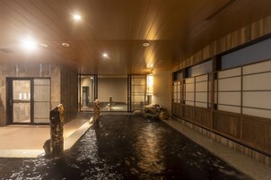 Un onsen japonés tradicional con interiores de madera, zona de aguas termales y una sala con esteras de tatami.