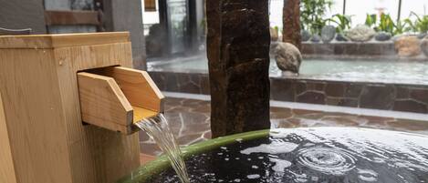 A wooden water feature with a stream of water flowing into a pond.