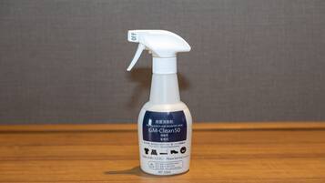 A bottle of GM-Clean 50 antibacterial and deodorant spray on a wooden surface.