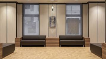 Un área de espera moderna con dos sofás, una mesa de centro de madera y ventanas amplias.