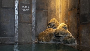Un muro de piedra con un letrero que dice "Cold Bath" y una fuente de agua con rocas.