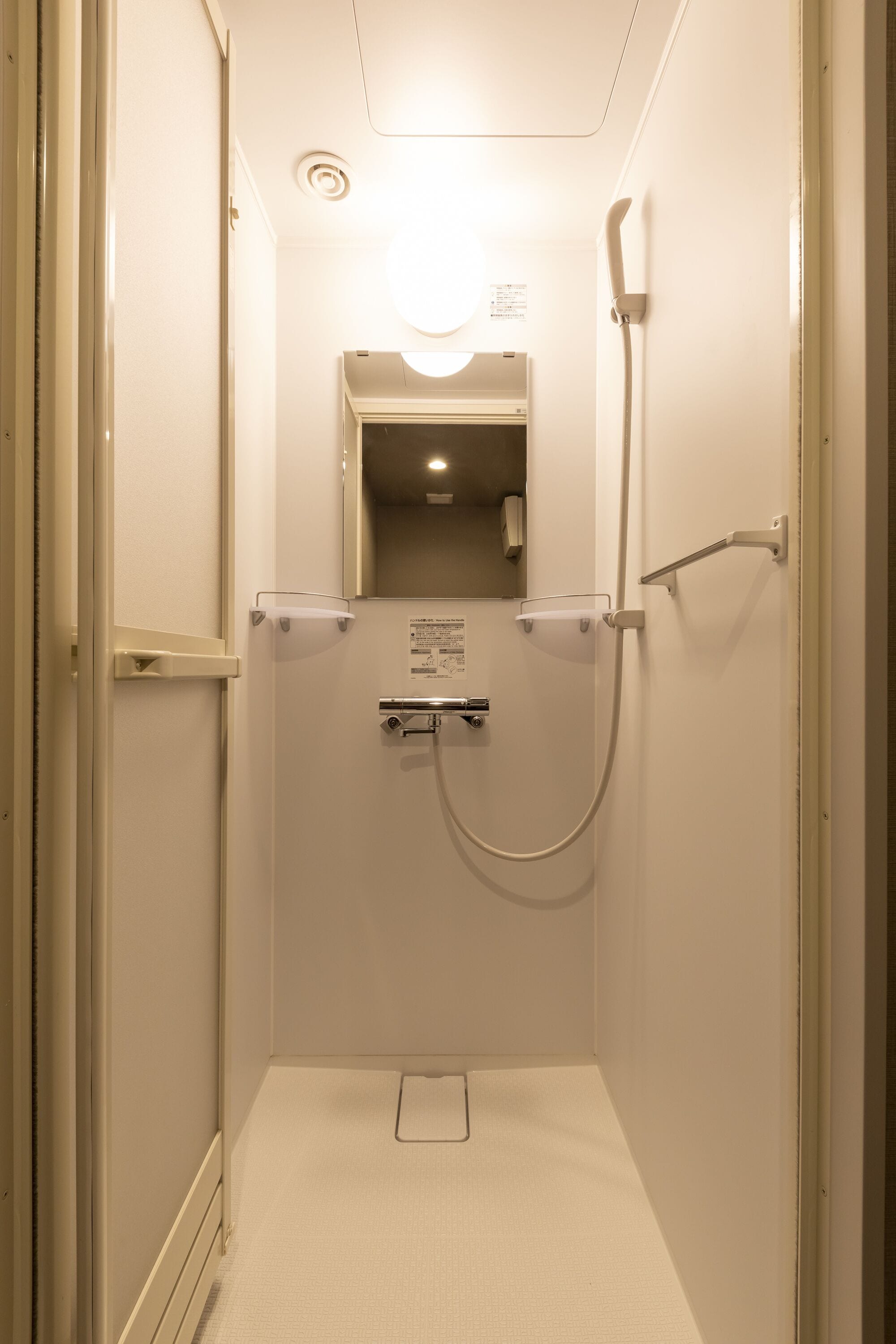 Eine kleine, geschlossene Duschkabine mit Handbrause und Wandarmatur.