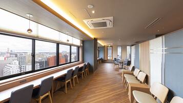 Una habitación de hotel moderna con ventanas amplias, suelo de madera y un mostrador de recepción alargado.