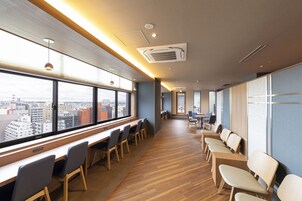 Una habitación de hotel moderna con ventanas amplias, suelo de madera y un mostrador de recepción alargado.