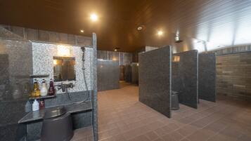 A modern bathroom with granite countertops, a shower area, and a tiled floor.