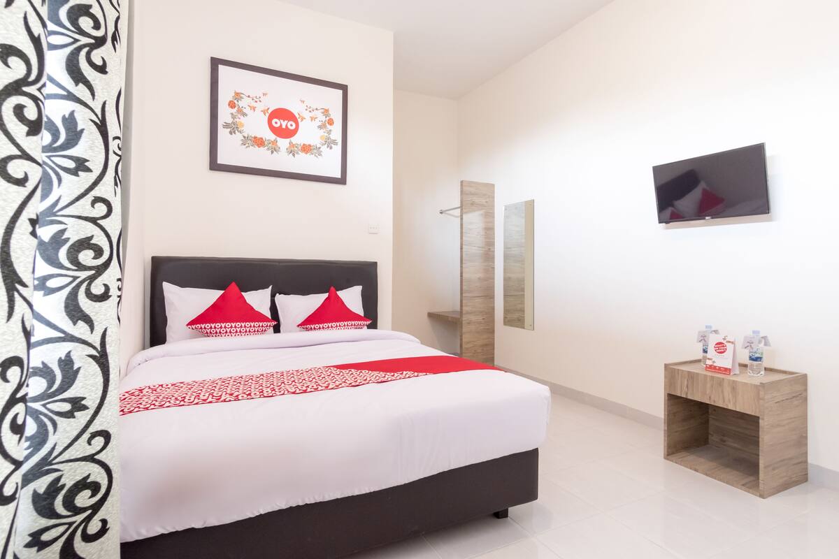 A neatly arranged bedroom with a bed, a bedside table, a mirror, and a framed picture on the wall.